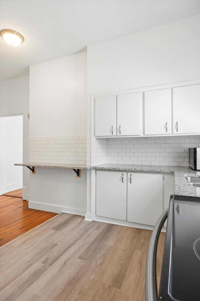 1306 Bailey Ave, Chattanooga, TN 37404 - kitchen with range, light wood finished floors, tasteful backsplash, and white cabinetry