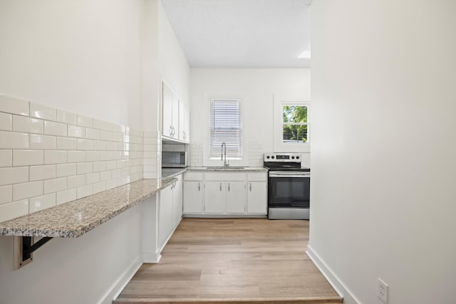 1306 Bailey Ave, Chattanooga, TN 37404 - kitchen with appliances with stainless steel finishes, light wood-style flooring, tasteful backsplash, white cabinets, and light stone counters