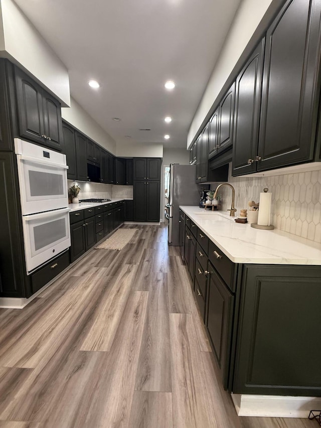120 Oakhurst Ter NE, Calhoun, GA 30701 - kitchen featuring appliances with stainless steel finishes, tasteful backsplash, light wood finished floors, light stone countertops, and recessed lighting