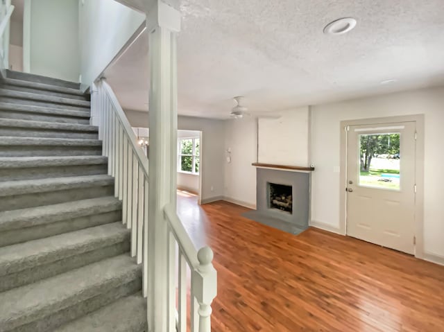 1116 Magnolia St, Lafayette, GA 30728 - stairs featuring wood finished floors, a fireplace with flush hearth, ceiling fan, and a textured ceiling