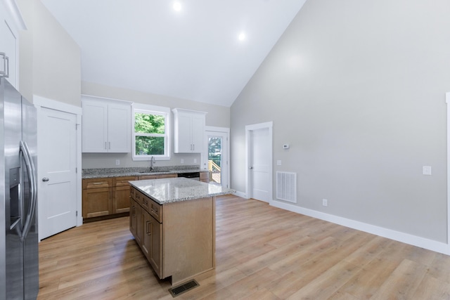 307 Cavender St, Lafayette, GA 30728 - kitchen with stainless steel fridge, high vaulted ceiling, a center island, light wood finished floors, and light stone counters