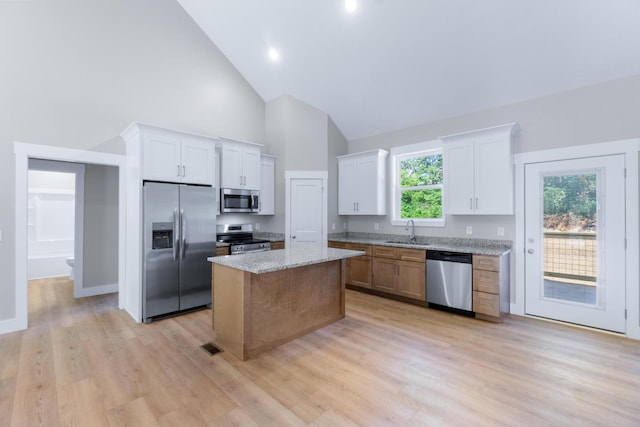 307 Cavender St, Lafayette, GA 30728 - kitchen featuring appliances with stainless steel finishes, high vaulted ceiling, white cabinets, a kitchen island, and light stone countertops