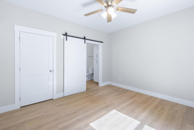 307 Cavender St, Lafayette, GA 30728 - unfurnished bedroom with a barn door, light wood-style floors, ensuite bath, and a ceiling fan
