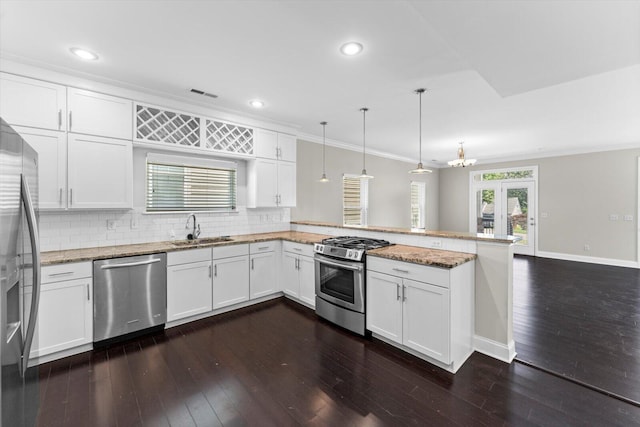1120 Valentine Cir, Chattanooga, TN 37405 - kitchen with appliances with stainless steel finishes, a peninsula, dark wood-style floors, decorative backsplash, and ornamental molding