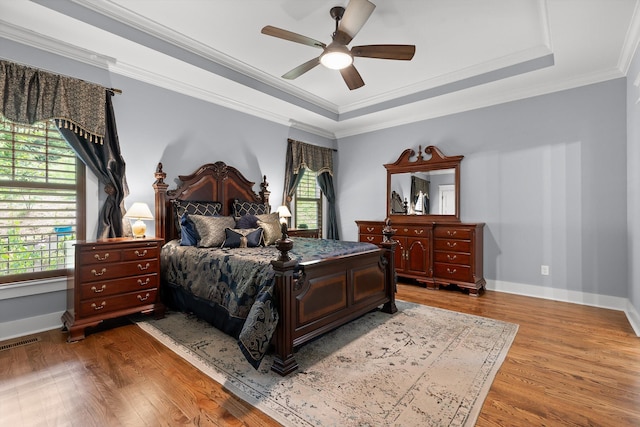 9795 Trestle Cir, Ooltewah, TN 37363 - bedroom featuring multiple windows, wood finished floors, a tray ceiling, ceiling fan, and crown molding