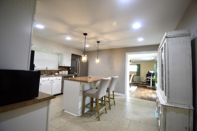268 Lawrence Dr, Rossville, GA 30741 - kitchen featuring stainless steel appliances, a kitchen island, white cabinets, a kitchen breakfast bar, and light tile patterned flooring
