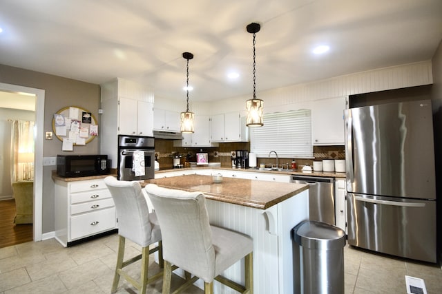 268 Lawrence Dr, Rossville, GA 30741 - kitchen featuring appliances with stainless steel finishes, under cabinet range hood, white cabinets, a kitchen island, and light tile patterned floors