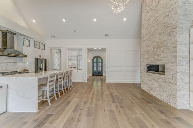 807 Judd Ter, Dalton, GA 30720 - kitchen with wall chimney exhaust hood, high vaulted ceiling, light wood-style flooring, light stone countertops, and stainless steel refrigerator with ice dispenser