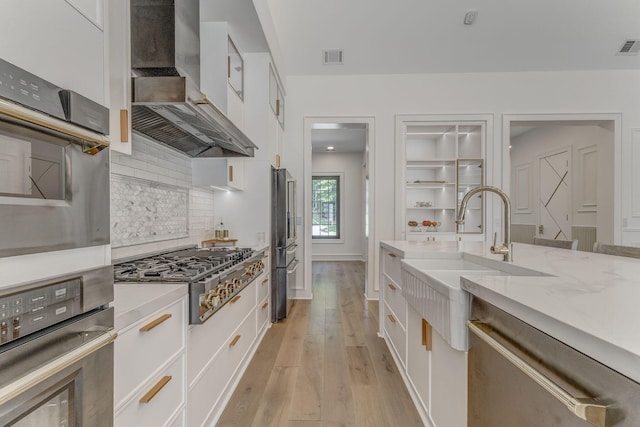 807 Judd Ter, Dalton, GA 30720 - kitchen with wall chimney exhaust hood, stainless steel appliances, decorative backsplash, light wood-style flooring, and white cabinetry