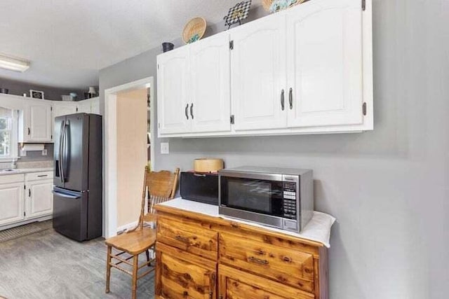 346 Thomas Rd, Benton, TN 37307 - kitchen with fridge with ice dispenser, stainless steel microwave, white cabinetry, light wood finished floors, and light countertops