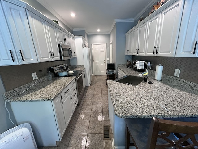 7901 Hamilton Mill Dr, Chattanooga, TN 37421 - kitchen featuring appliances with stainless steel finishes, ornamental molding, white cabinets, a breakfast bar area, and light stone counters