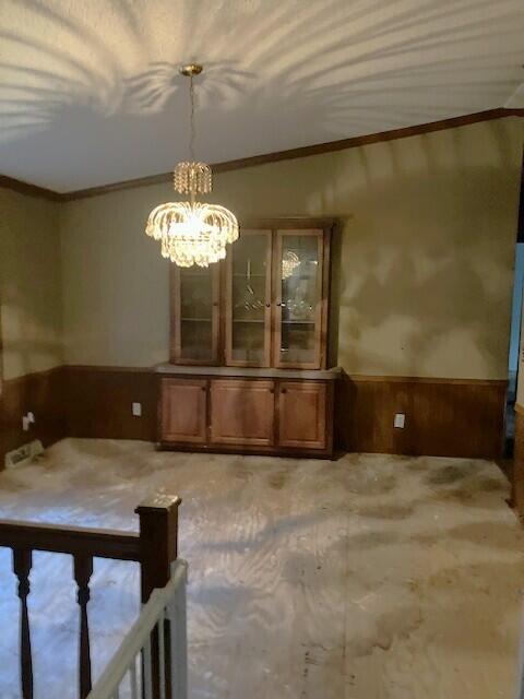 287 E Teems Rd, Ringgold, GA 30736 - unfurnished dining area with crown molding, a wainscoted wall, a chandelier, and wooden walls