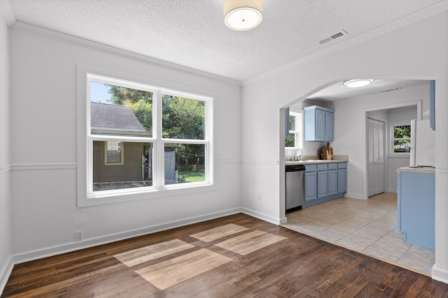 5014 Carolyn Ln, Chattanooga, TN 37411 - kitchen featuring blue cabinets, stainless steel dishwasher, light wood-style flooring, arched walkways, and a textured ceiling