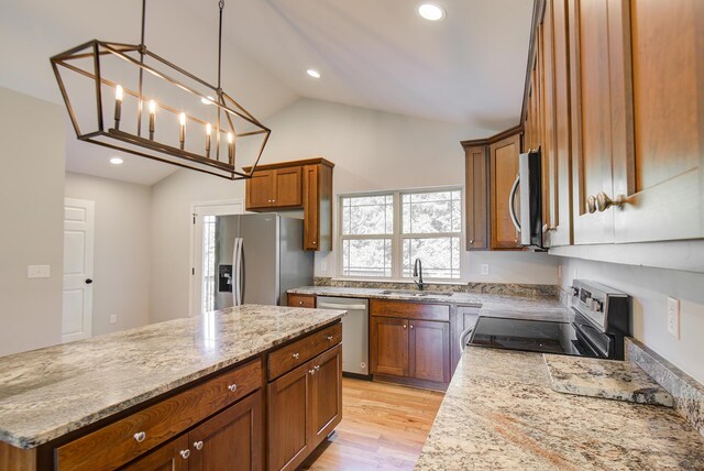 6253 River Stream Dr, Harrison, TN 37341 - kitchen with stainless steel appliances, light stone countertops, brown cabinetry, light wood-style flooring, and a kitchen island