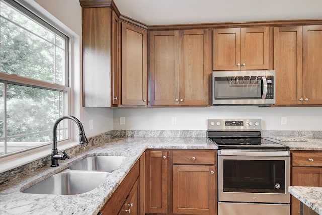 6253 River Stream Dr, Harrison, TN 37341 - kitchen with appliances with stainless steel finishes, plenty of natural light, brown cabinetry, and light stone countertops