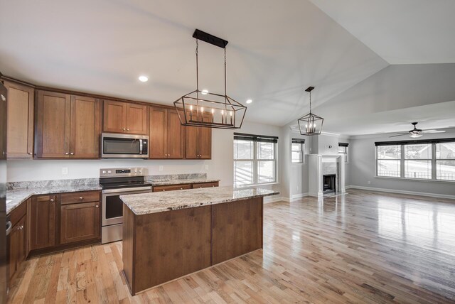 6253 River Stream Dr, Harrison, TN 37341 - kitchen with stainless steel appliances, a kitchen island, light stone counters, decorative light fixtures, and light wood-style floors