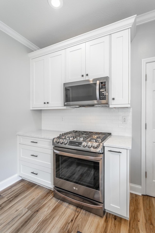 846 Altamont Rd, Chattanooga, TN 37415 - kitchen with stainless steel appliances, crown molding, light wood-style floors, white cabinetry, and tasteful backsplash