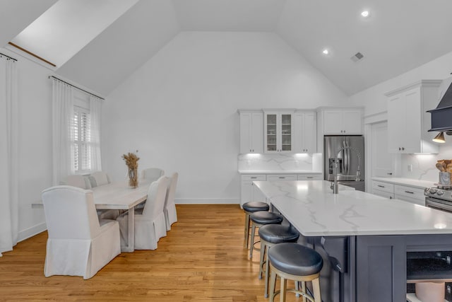 9253 Skyfall Dr, Ooltewah, TN 37363 - kitchen with appliances with stainless steel finishes, high vaulted ceiling, white cabinetry, a breakfast bar, and glass insert cabinets