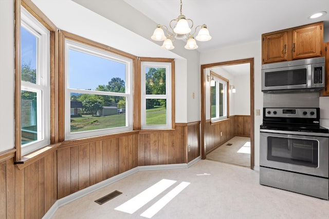 4920 Pine Cir, Ooltewah, TN 37363 - kitchen with stainless steel appliances, wainscoting, a chandelier, wooden walls, and brown cabinetry