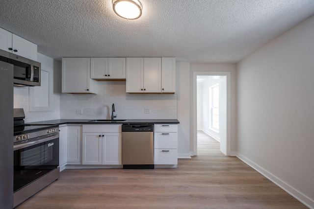 103 Laurel Dr, Chattanooga, TN 37415 - kitchen with appliances with stainless steel finishes, dark countertops, backsplash, a textured ceiling, and white cabinetry