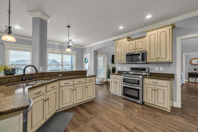 7459 Red Poppy Dr, Ooltewah, TN 37363 - kitchen with appliances with stainless steel finishes, cream cabinets, dark wood-style floors, arched walkways, and crown molding