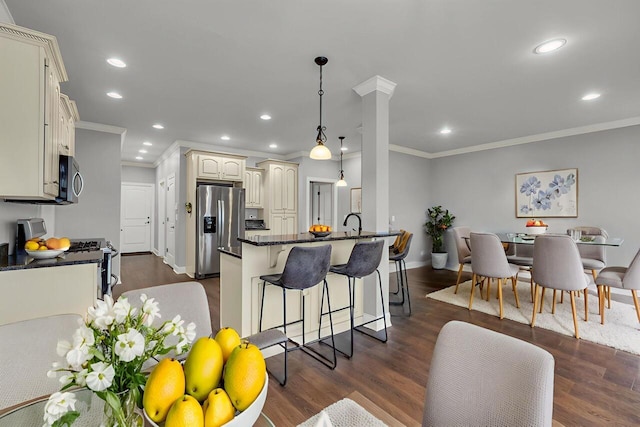 7459 Red Poppy Dr, Ooltewah, TN 37363 - kitchen with stainless steel appliances, cream cabinetry, a breakfast bar, crown molding, and a peninsula