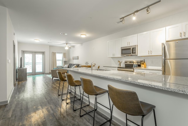 804 Riverfront Pkwy Unit 401, Chattanooga, TN 37402 - kitchen with appliances with stainless steel finishes, tasteful backsplash, open floor plan, dark wood-style floors, and white cabinetry