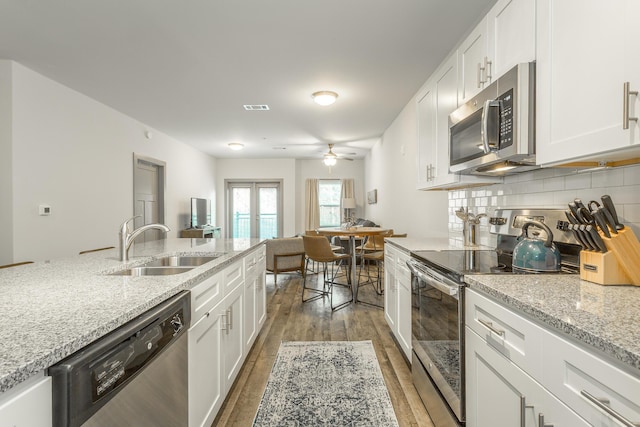 804 Riverfront Pkwy Unit 401, Chattanooga, TN 37402 - kitchen featuring appliances with stainless steel finishes, wood finished floors, white cabinets, ceiling fan, and tasteful backsplash