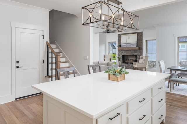 234 Goose Creek Cir, Soddy Daisy, TN 37379 - kitchen featuring light wood-type flooring, a stone fireplace, a center island, and ceiling fan