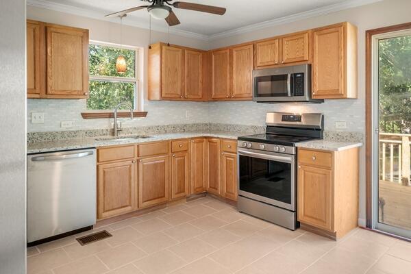 3224 Through St, Chattanooga, TN 37411 - kitchen with appliances with stainless steel finishes, a ceiling fan, crown molding, tasteful backsplash, and light tile patterned flooring