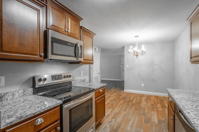 900 Mountain Creek Rd Unit P224, Chattanooga, TN 37405 - kitchen featuring appliances with stainless steel finishes, light wood-style flooring, a chandelier, light stone counters, and brown cabinets