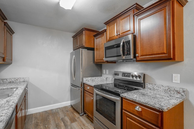 900 Mountain Creek Rd Unit P224, Chattanooga, TN 37405 - kitchen with stainless steel appliances, wood finished floors, brown cabinetry, and light stone countertops