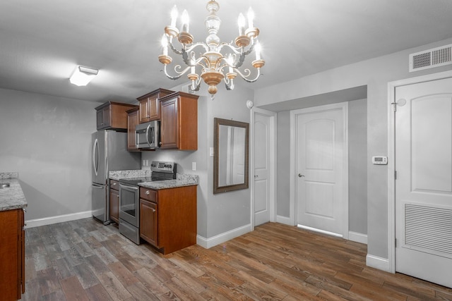 900 Mountain Creek Rd Unit P224, Chattanooga, TN 37405 - kitchen featuring appliances with stainless steel finishes, brown cabinetry, dark wood finished floors, light stone counters, and a chandelier