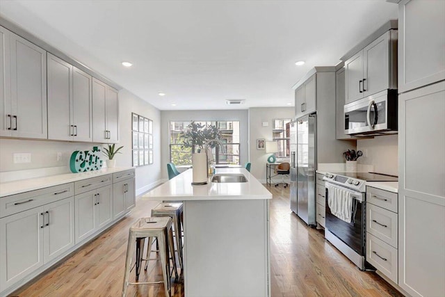 280 W 16th St, Chattanooga, TN 37408 - kitchen featuring stainless steel appliances, light wood-type flooring, a center island with sink, light countertops, and recessed lighting