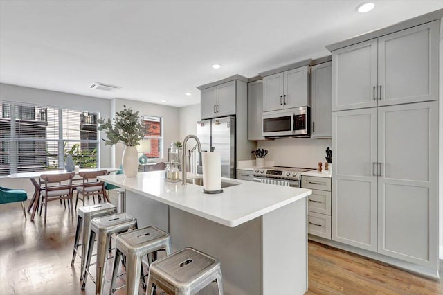 280 W 16th St, Chattanooga, TN 37408 - kitchen with stainless steel appliances, gray cabinets, a breakfast bar area, a kitchen island with sink, and light countertops