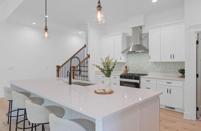 8340 Snowdrop Way, Ooltewah, TN 37363 - kitchen featuring wall chimney range hood, gas stove, light wood-style flooring, tasteful backsplash, and white cabinetry