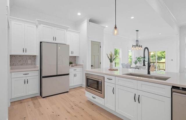 8340 Snowdrop Way, Ooltewah, TN 37363 - kitchen with appliances with stainless steel finishes, light countertops, white cabinetry, decorative backsplash, and crown molding