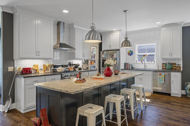 834 Dartmouth St, Chattanooga, TN 37405 - kitchen featuring wall chimney range hood, appliances with stainless steel finishes, decorative backsplash, dark wood-type flooring, and recessed lighting