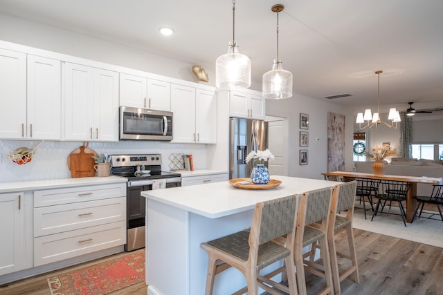 8520 Kensley Ln, Hixson, TN 37343 - kitchen with stainless steel appliances, light countertops, tasteful backsplash, light wood-type flooring, and a breakfast bar area