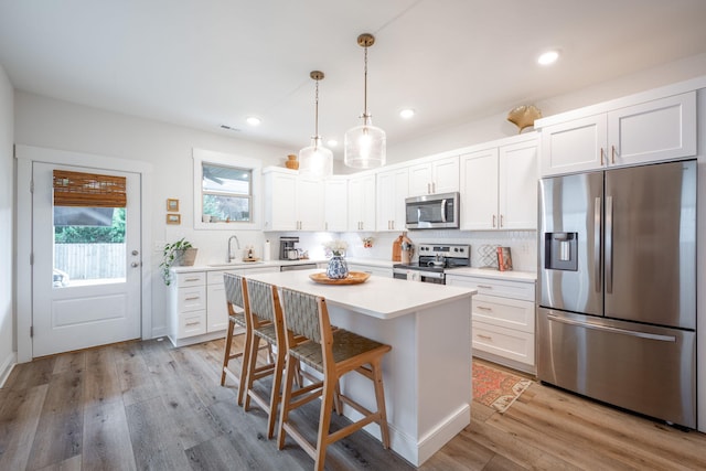 8520 Kensley Ln, Hixson, TN 37343 - kitchen featuring stainless steel appliances, white cabinets, light countertops, a breakfast bar area, and a kitchen island