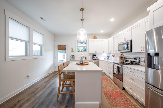 8520 Kensley Ln, Hixson, TN 37343 - kitchen featuring stainless steel appliances, wood finished floors, light countertops, white cabinets, and a breakfast bar area