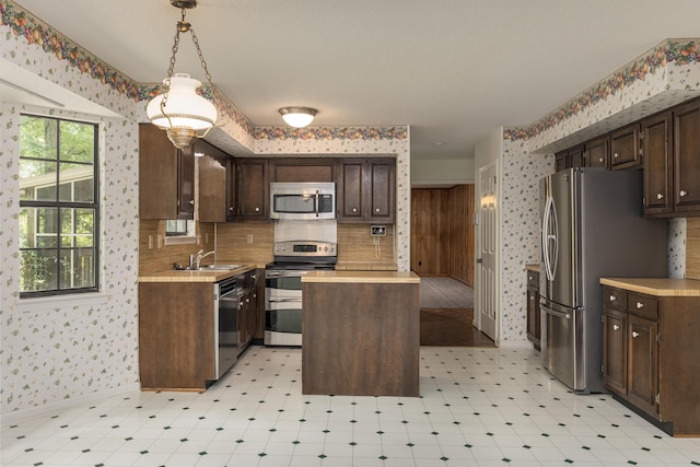 6515 Lake Shadows Cir, Hixson, TN 37343 - kitchen with wallpapered walls, light countertops, a kitchen island, dark brown cabinetry, and stainless steel appliances