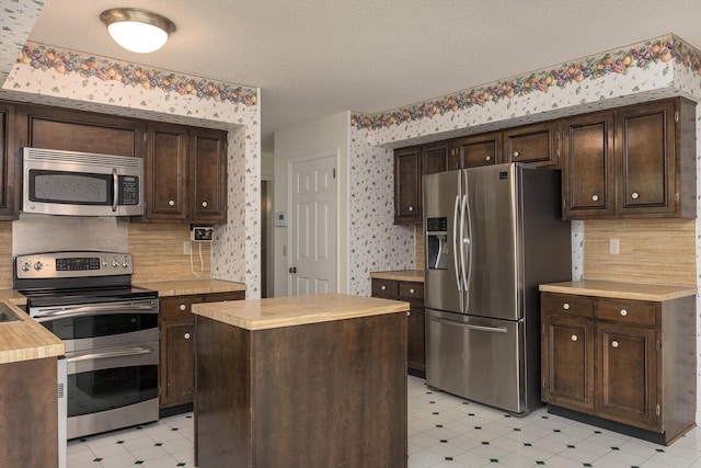 6515 Lake Shadows Cir, Hixson, TN 37343 - kitchen with light flooring, wallpapered walls, appliances with stainless steel finishes, dark brown cabinets, and backsplash