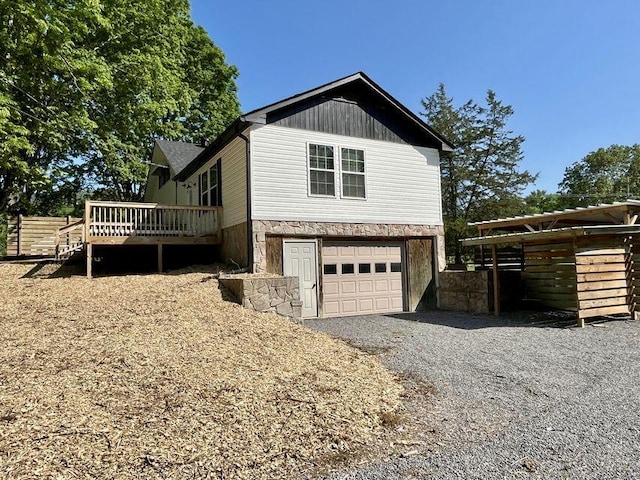 6248 Old Dunlap Rd, Whitwell, TN 37397 - view of property exterior featuring stone siding, an attached garage, a wooden deck, and gravel driveway