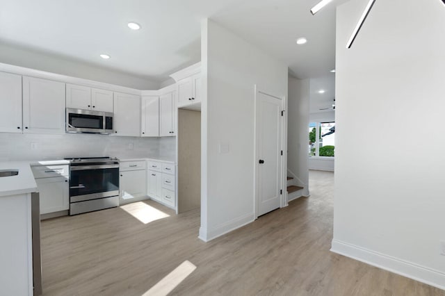 1306 Top St, Chattanooga, TN 37408 - kitchen featuring stainless steel appliances, light wood-style floors, backsplash, light countertops, and white cabinets
