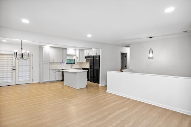 2427 Maplewood Dr, Chattanooga, TN 37421 - kitchen with black fridge, light wood-type flooring, light countertops, tasteful backsplash, and a chandelier