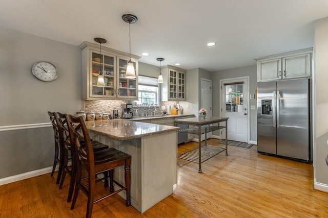 212 Cox Ln, Soddy Daisy, TN 37379 - kitchen featuring stainless steel refrigerator with ice dispenser, a peninsula, light wood-type flooring, decorative backsplash, and hanging light fixtures