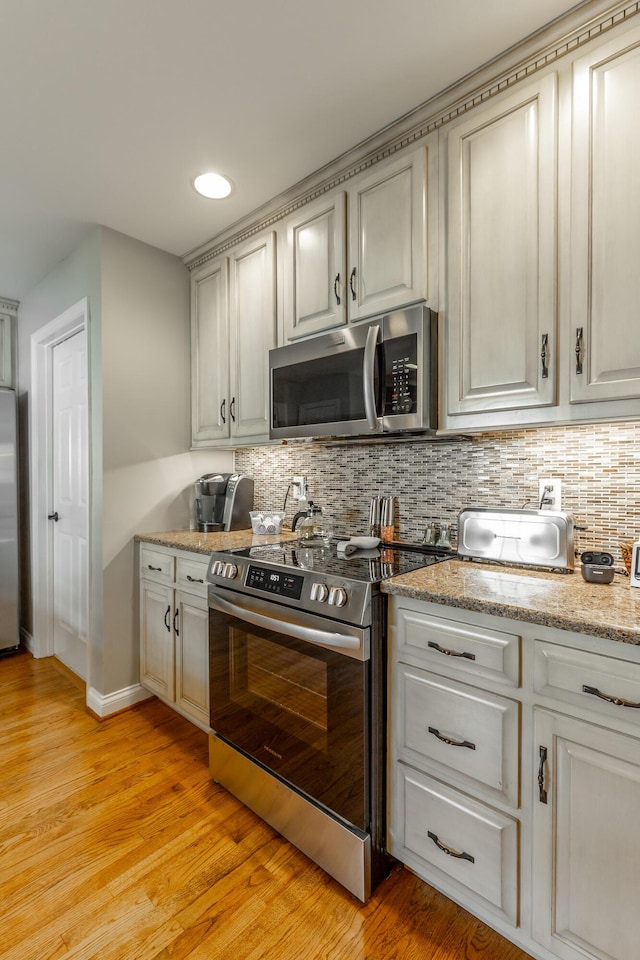 212 Cox Ln, Soddy Daisy, TN 37379 - kitchen with appliances with stainless steel finishes, backsplash, light wood-style floors, and light stone countertops