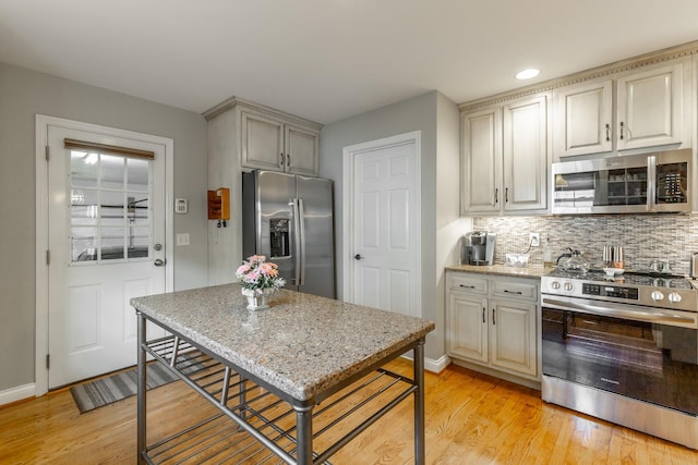 212 Cox Ln, Soddy Daisy, TN 37379 - kitchen with appliances with stainless steel finishes, light wood-style flooring, decorative backsplash, and light stone countertops