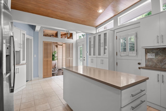 2554 Crestwood Dr, Chattanooga, TN 37415 - kitchen featuring wooden ceiling, decorative backsplash, light tile patterned flooring, a center island, and glass insert cabinets